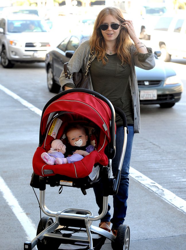 Amy Adams, red baby carrier, red car seat, gray sweater, sunglasses, jeans, brown long sleeved shirt